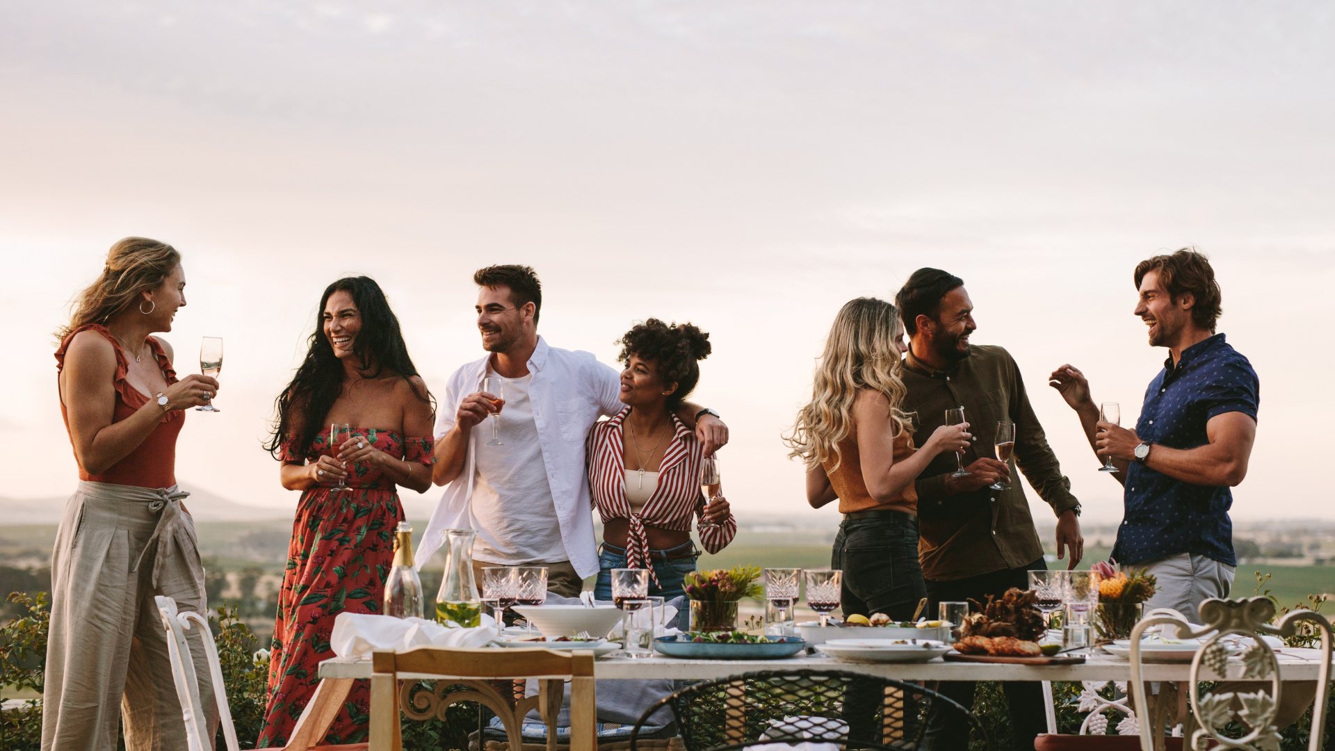 Rassemblement convivial autour d'une grande tablée en plein air au coucher de soleil