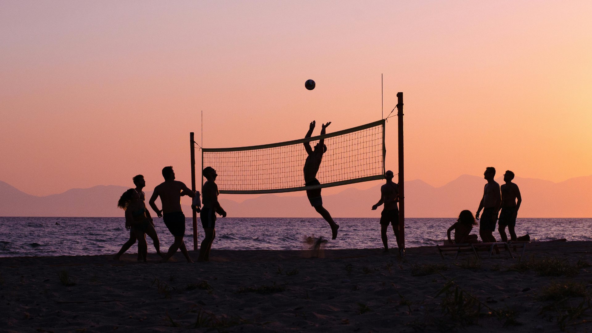 Partie de beach-volley en silhouette au coucher de soleil, au bord de la mer