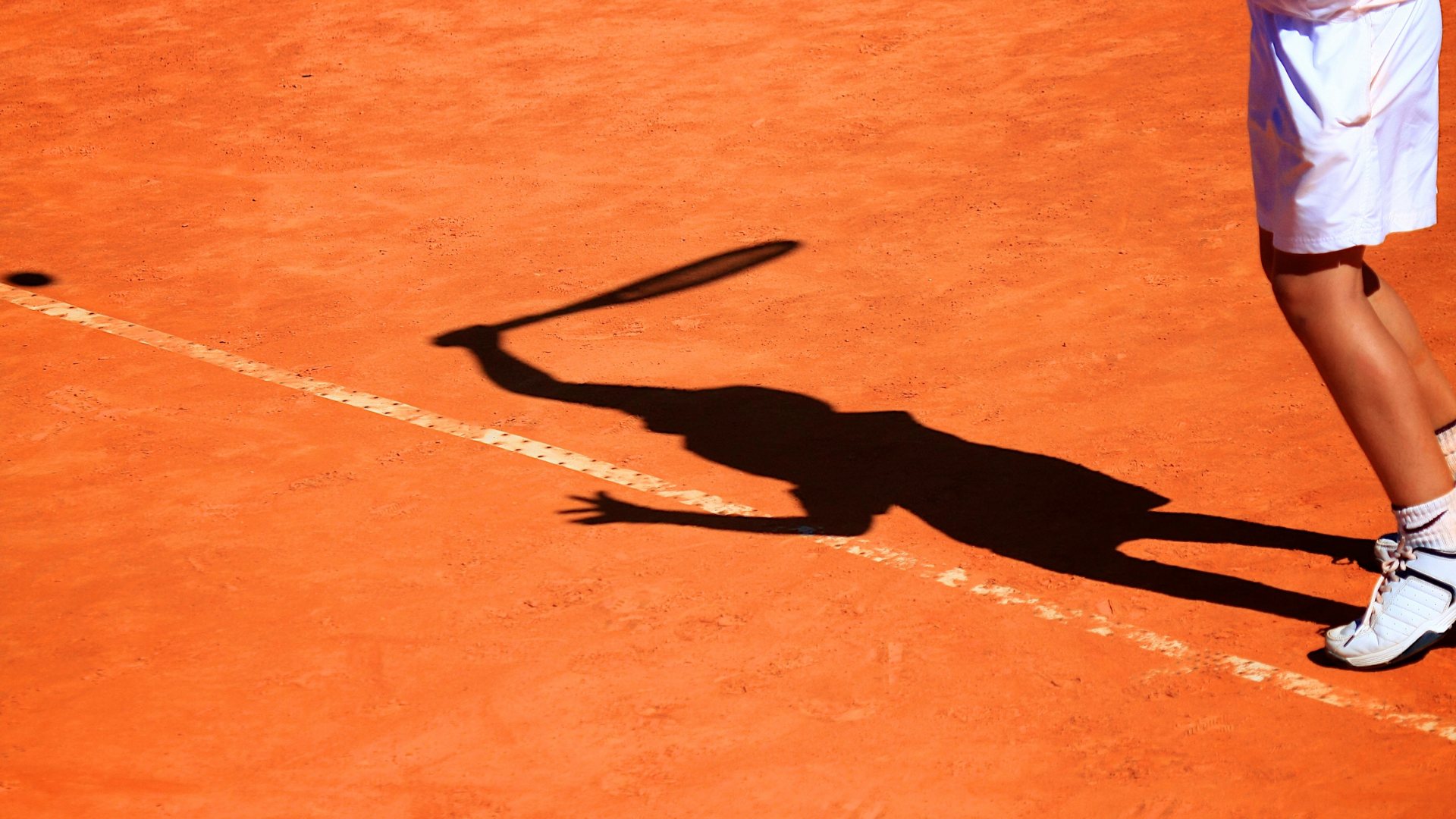 Ombre d'un joueur de tennis sur terre battue, geste de frappe