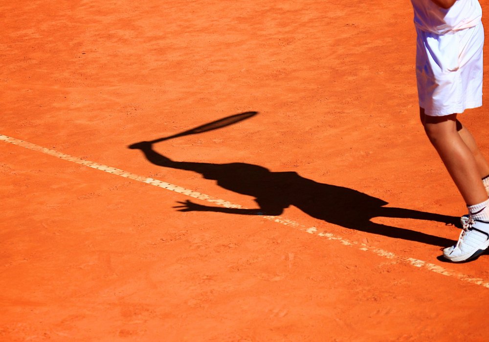 Ombre d'un joueur de tennis sur terre battue, geste de service
